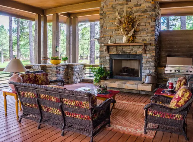 Stone fireplace in a bright garden room with wicker sofas and cushions